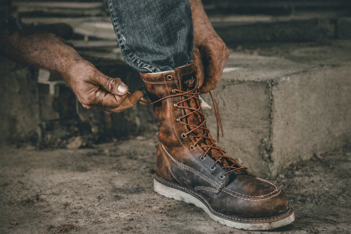 Work boots vs work shoes comparison image showing a worker lacing a rugged safety boot on a job site