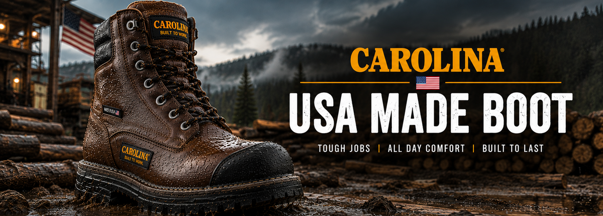 A brown leather Carolina work boot with a black toe cap and laces, shown in a rugged outdoor setting with logs, mountains, and a cabin.