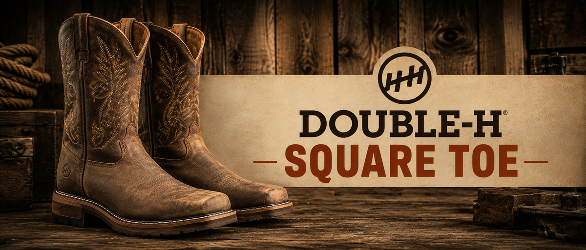 A pair of brown western cowboy boots with embroidered stitching, displayed on a rustic wooden surface next to a branded sign that reads 'DOUBLE-H SQUARE TOE' with a Double-H logo.