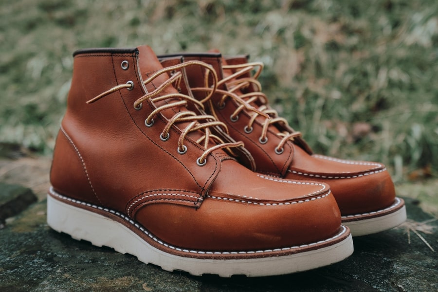 Close-up of composite toe wedge boots on a job site with gravel and tools in the background.