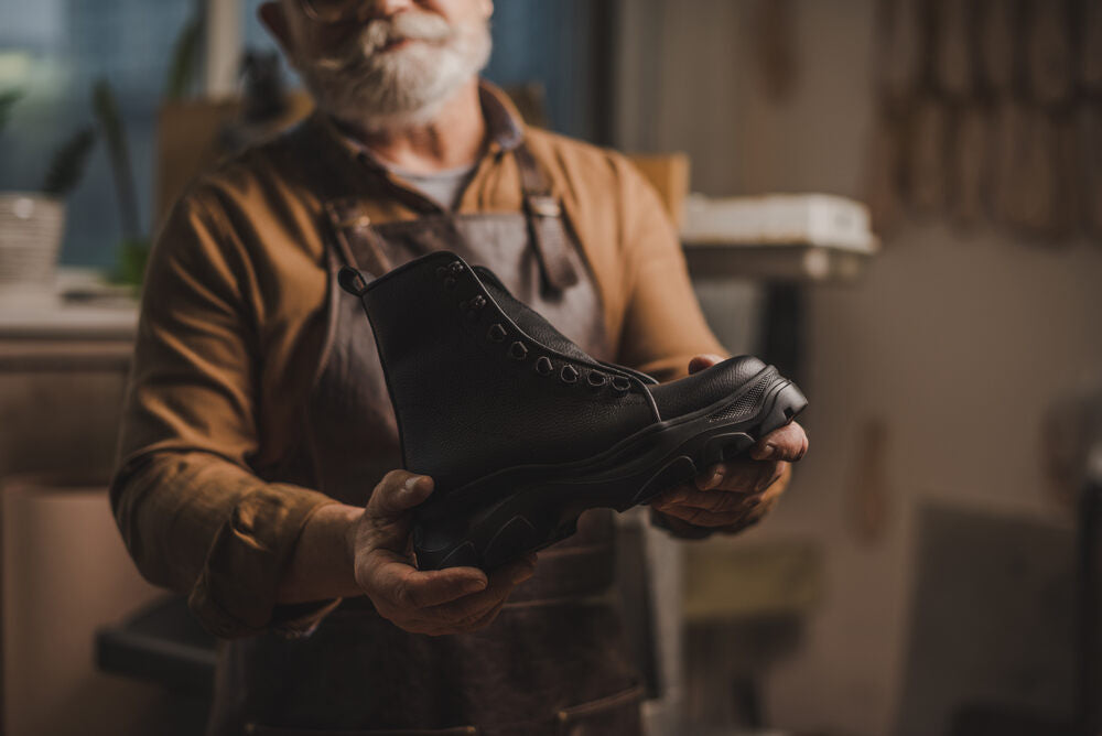 An old worker is holding work boot