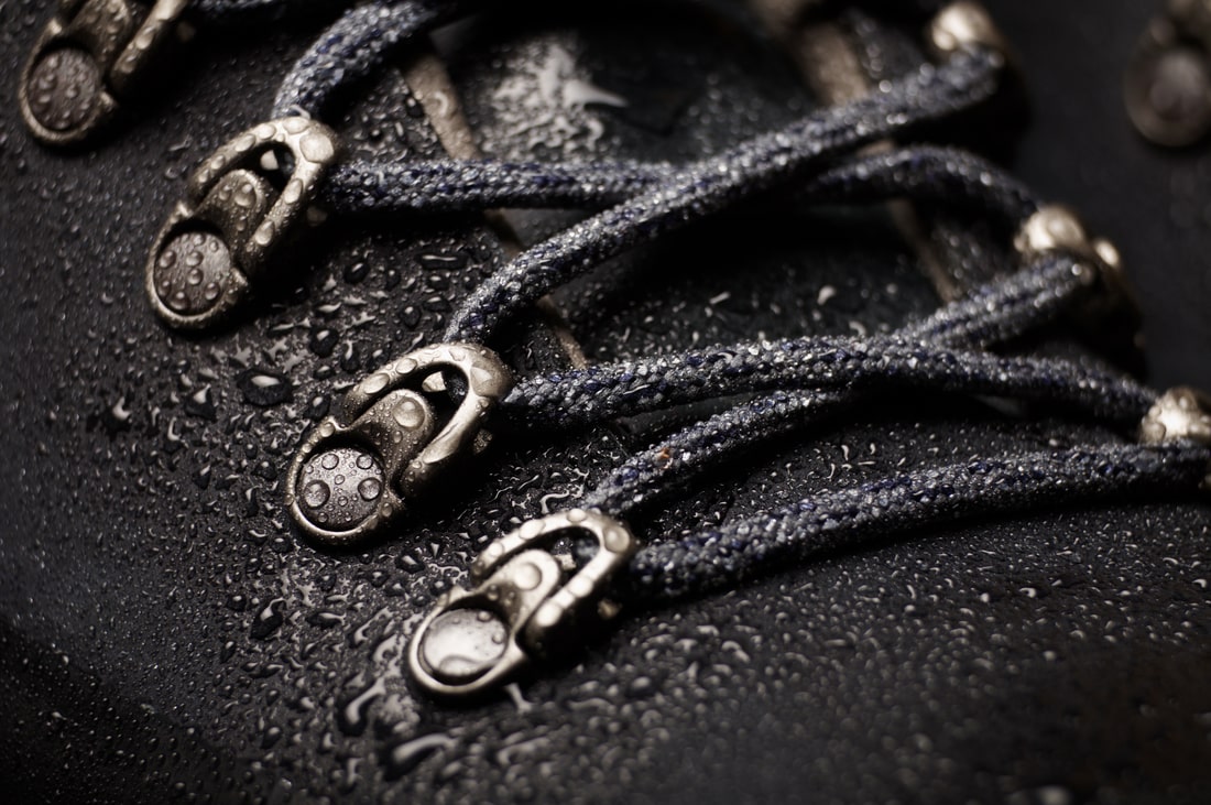 A black waterproof leather winter boot with water drops.