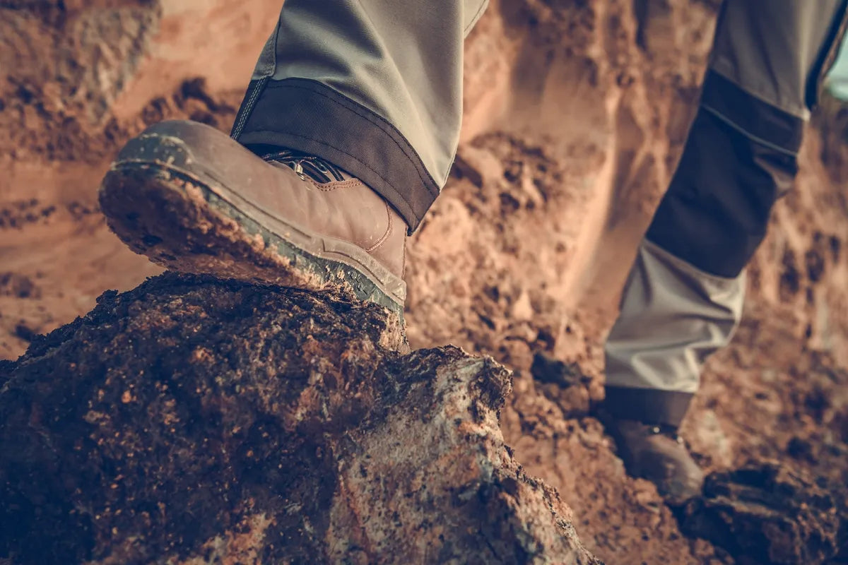 close up of worker's legs in Carolina work boots standing on the road