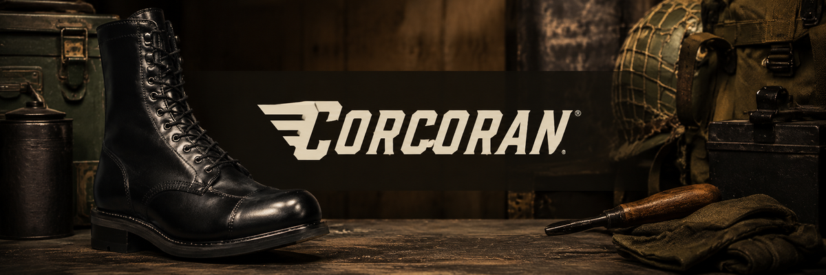 A black leather lace-up boot is displayed on a rustic wooden surface with military-themed props, including a helmet, knife, and gear, under a dark banner with the white Corcoran logo.