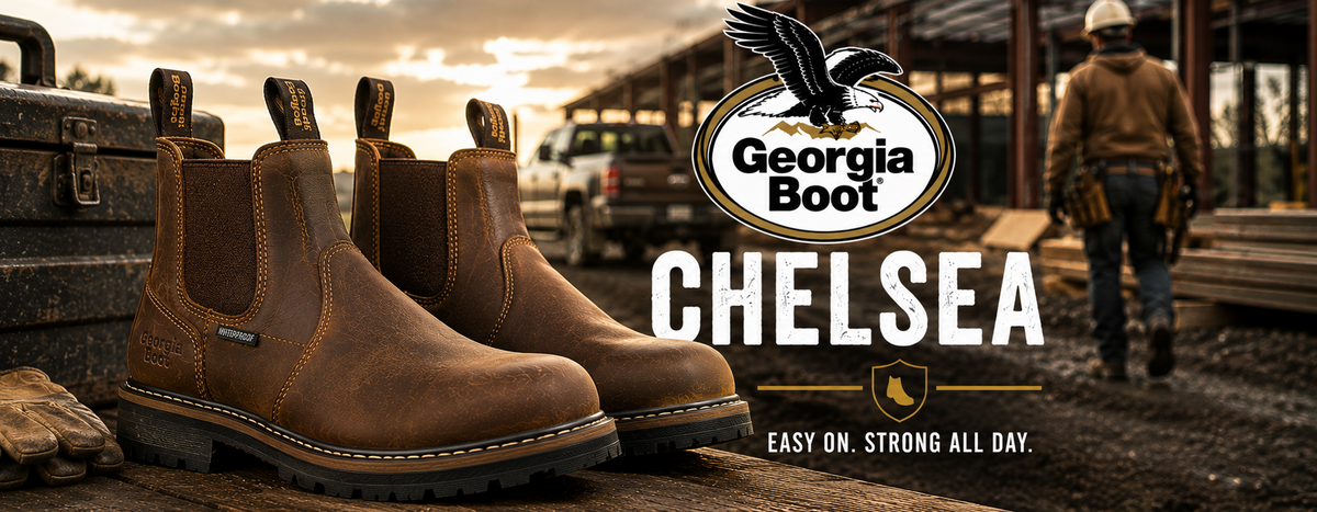 A pair of brown Chelsea-style work boots displayed on a wooden surface in a construction site setting, with the Georgia Boot Chelsea branding and slogan overlaid on the right side.